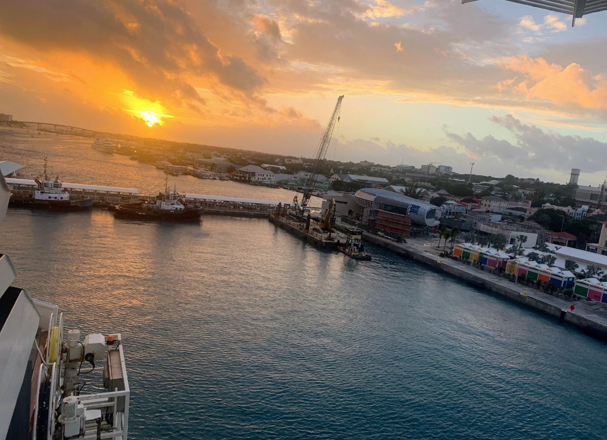 Golden Sunset Over the Harbor Sunset over a Caribbean port with boats and cranes along the shoreline.